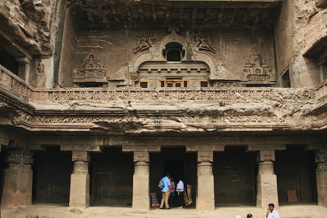 Group of people standing in front of grand building with pillars.