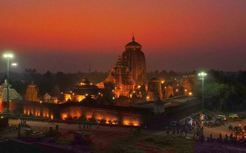 A majestic temple at sunset, bustling with people strolling around its premises.