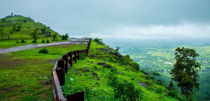 Scenic green valley with wooden fence in foreground.