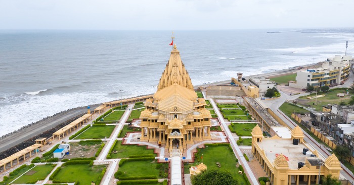 Temple on a serene beach with white sand, and crystal clear blue water under a clear blue sky.