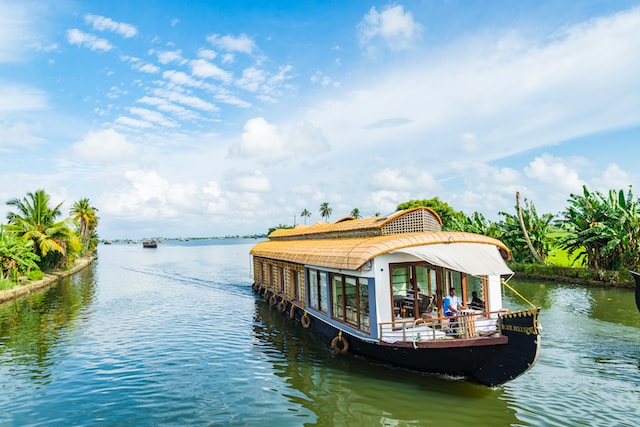 Houseboat sailing over a calm river water with beautiful blue sky at the top