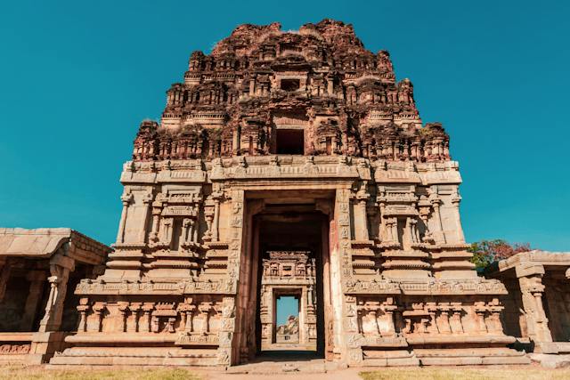 Entrance to ancient Indian temple with intricate carvings and stone pillars.