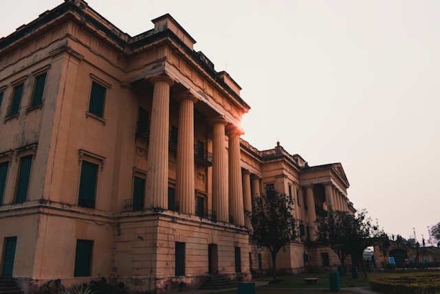 Sunset behind a columned building, casting a warm glow on the surroundings.