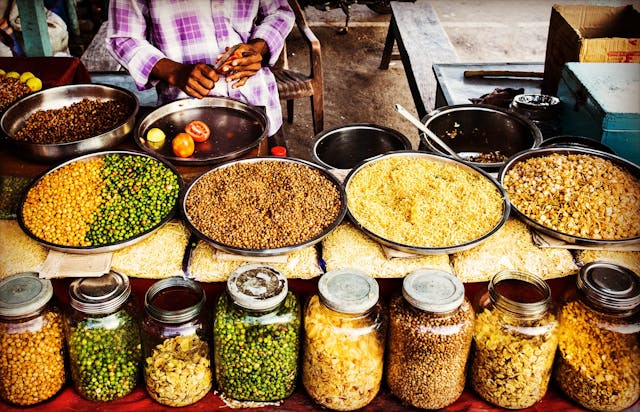 A man stands before a table filled with a variety of food options, showcasing a tempting array of culinary delights.