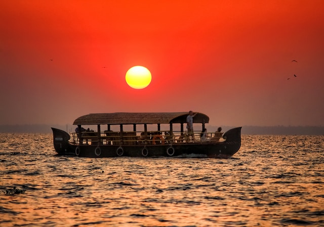 A beautiful sunset over a boat in a calm lake, with vibrant orange and pink hues reflecting on the water.