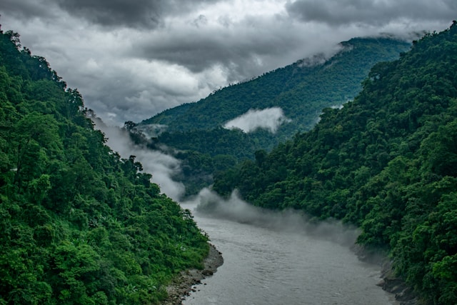 A beautiful river meandering through a vibrant green valley, surrounded by lush vegetation and breathtaking natural beauty.