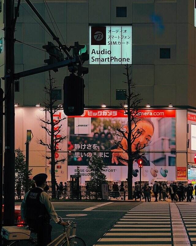 A policeman on a bicycle waits at a crosswalk one night in Akihabara, Chiyoda City, Tokyo, Japan.