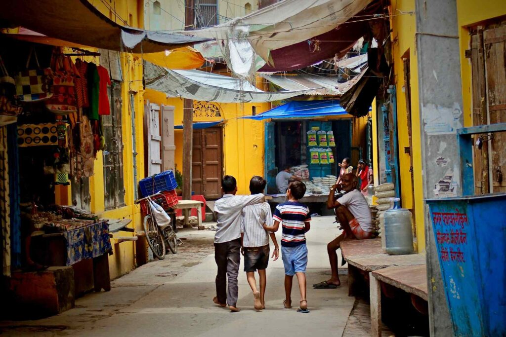 Three children walking down a narrow alley in India