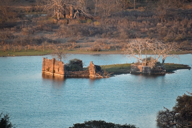 An ancient ruin stands amidst a serene lake, showcasing the passage of time and the beauty of nature