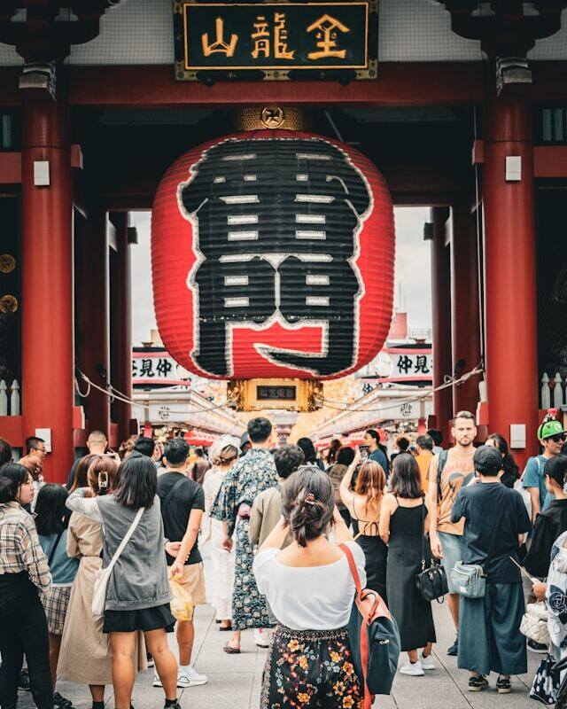 Tourists at Tokyo temple entrance, admiring its beauty and cultural significance.