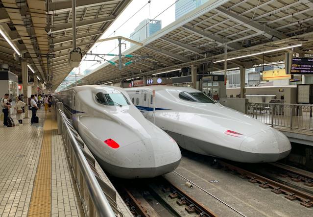 Two bullet trains parked at a station, ready to transport passengers efficiently and swiftly