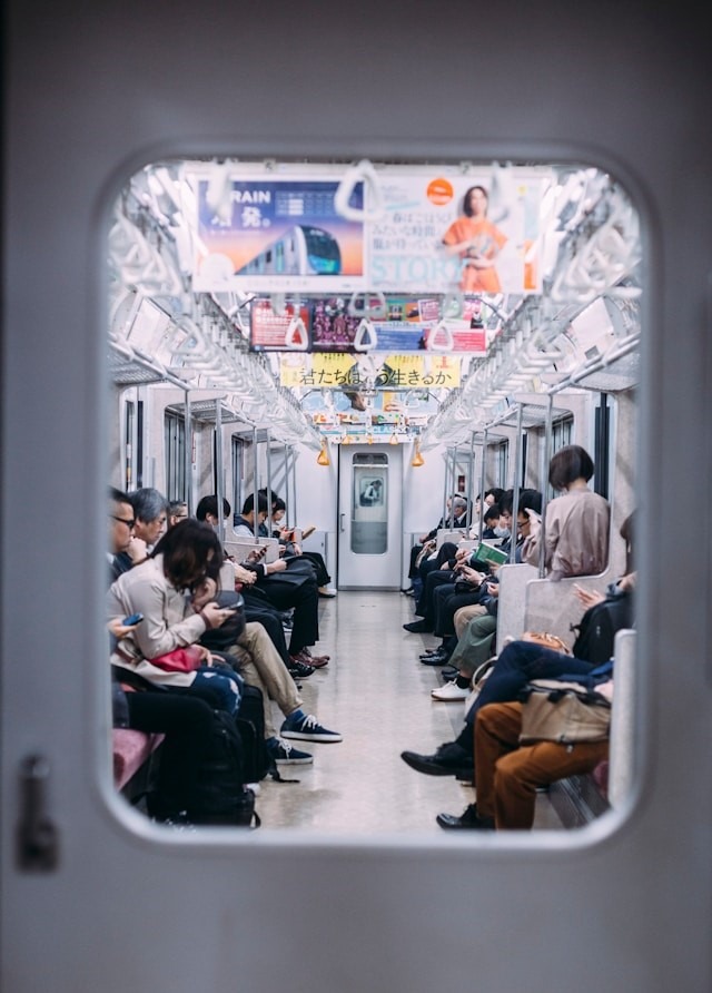 People sitting on a subway train, engrossed in their own thoughts and activities.a