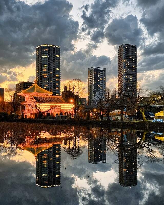 City skyline reflecting in water. A picturesque view of urban architecture mirrored on the calm surface.