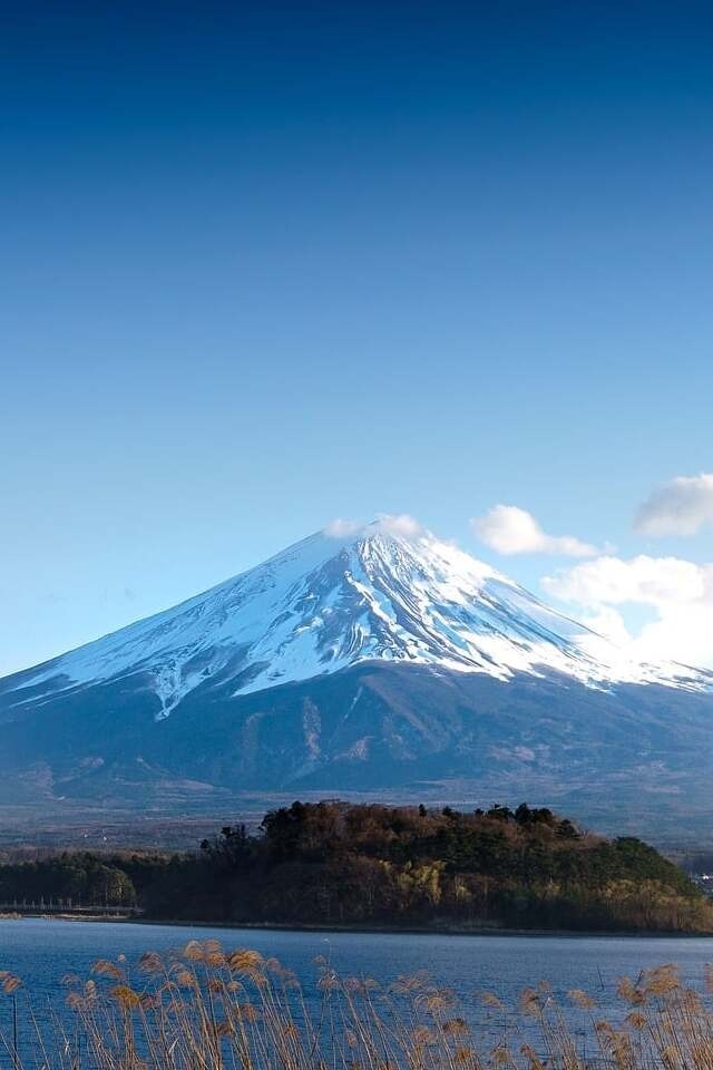 Iconic Mount Fuji in Japan, surrounded by serene landscapes and clear blue skies.