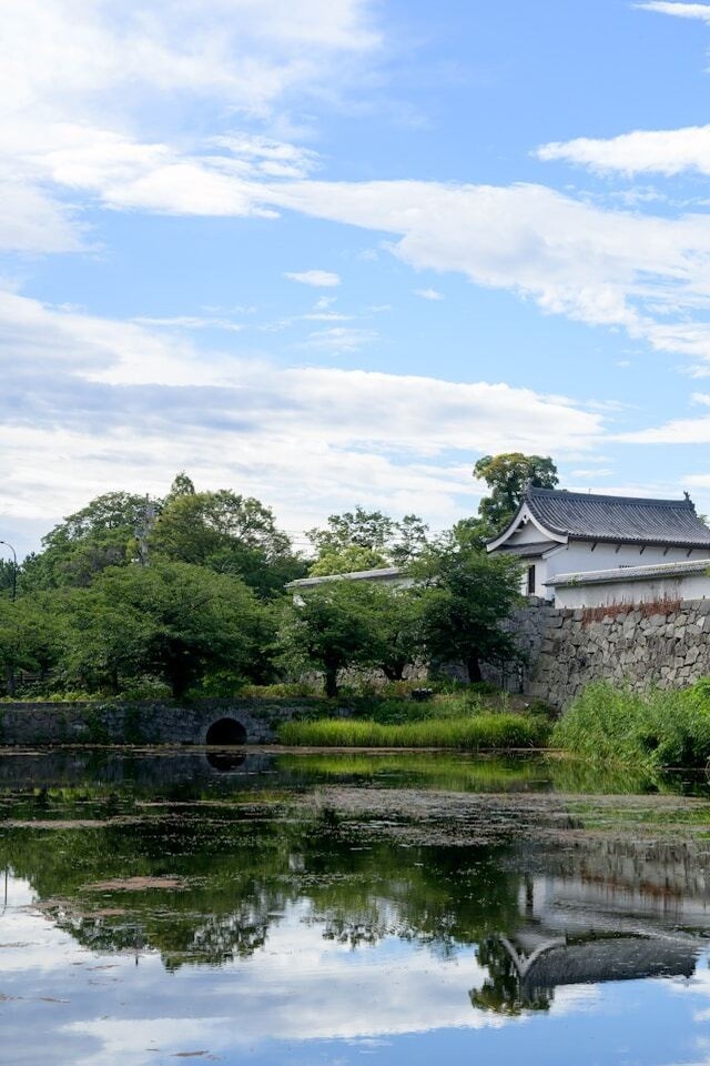 A serene pond with a bridge and a distant Fukuoka Castle in the background, creating a picturesque scene.