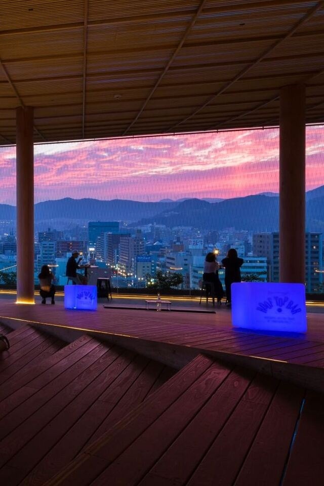 A group of people sitting on a wooden deck, enjoying the view of the city below.