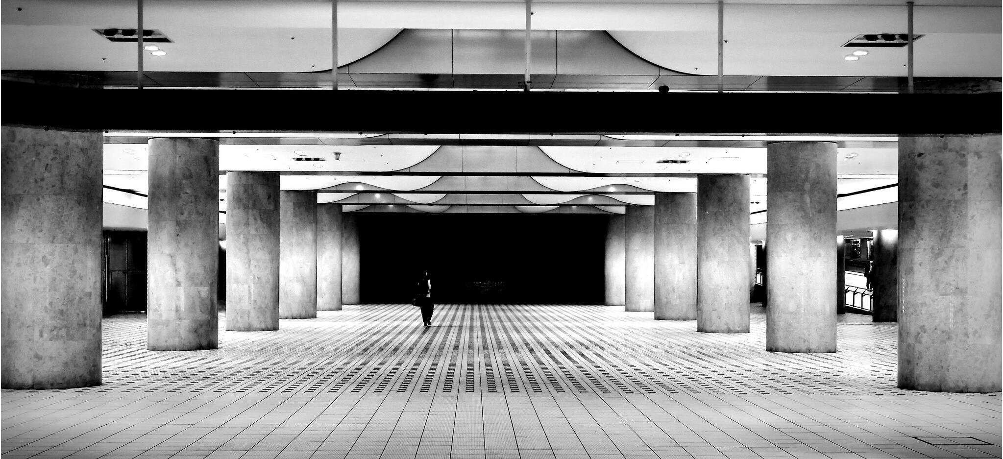 A person walking through a building in a black and white photo.