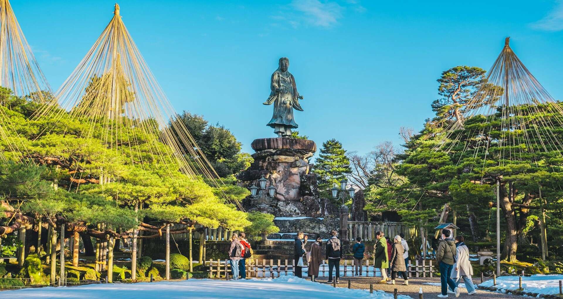 Statue in a garden surrounded by lush green trees.