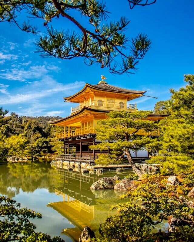 Golden Pavilion in Kyoto, Japan, known as Kinkakuji, surrounded by lush greenery and reflecting in a tranquil pond.