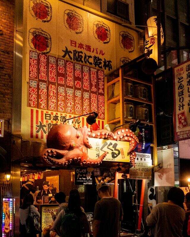 People gathered outside a restaurant, some looking at menus, others checking their phones.