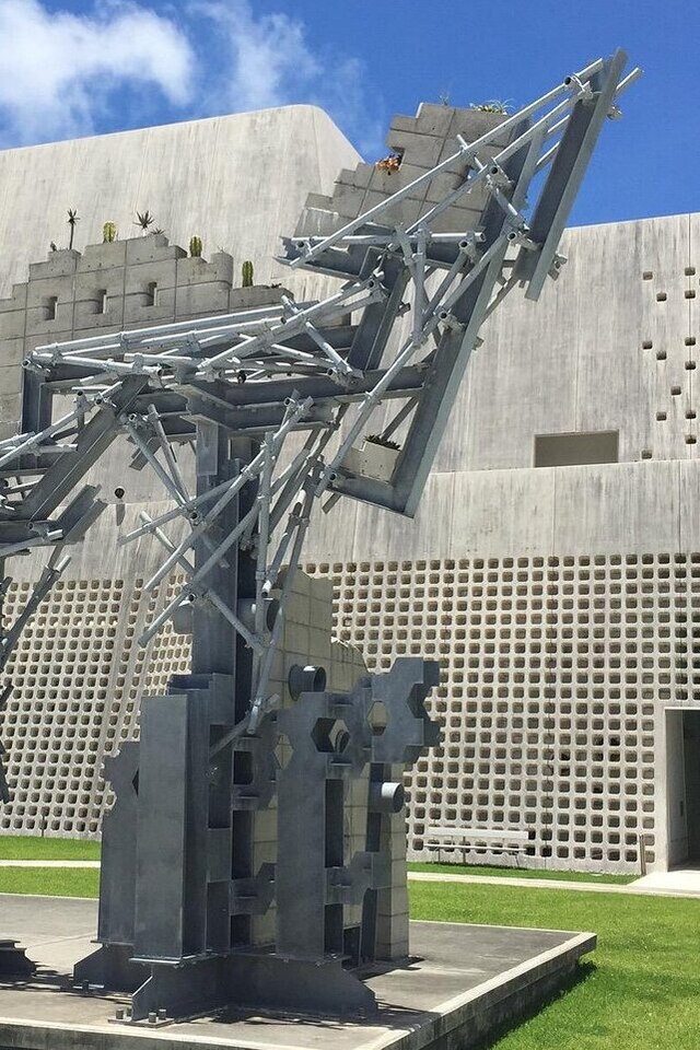 A large metal sculpture stands in front of a building, showcasing an intricate and captivating design.