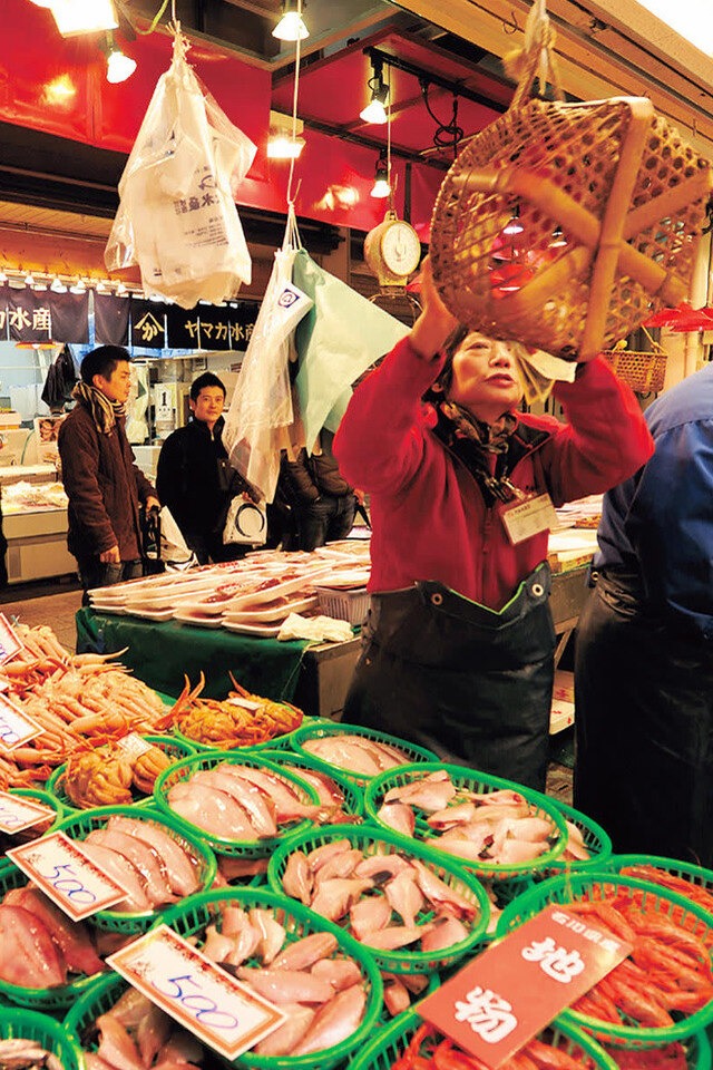 A woman holding up a fish in a market