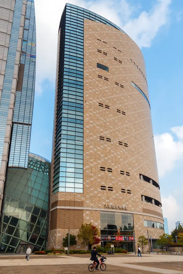 A modern skyscraper next to a unique, curved roof building.