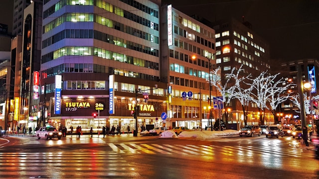 A bustling city street at night, illuminated by vibrant lights, showcasing the vibrant energy and activity of urban life.