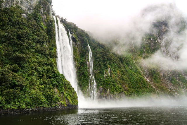 A serene waterfall nestled amidst vibrant green trees, creating a picturesque scene of natural beauty.