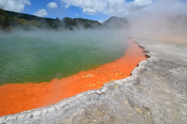 Vibrant orange and green water with billowing steam rising from it.