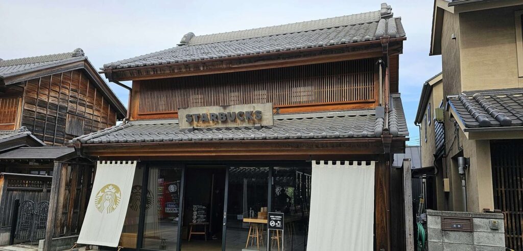 Starbucks in japan in a Small traditional building with wooden roof, sign on door.